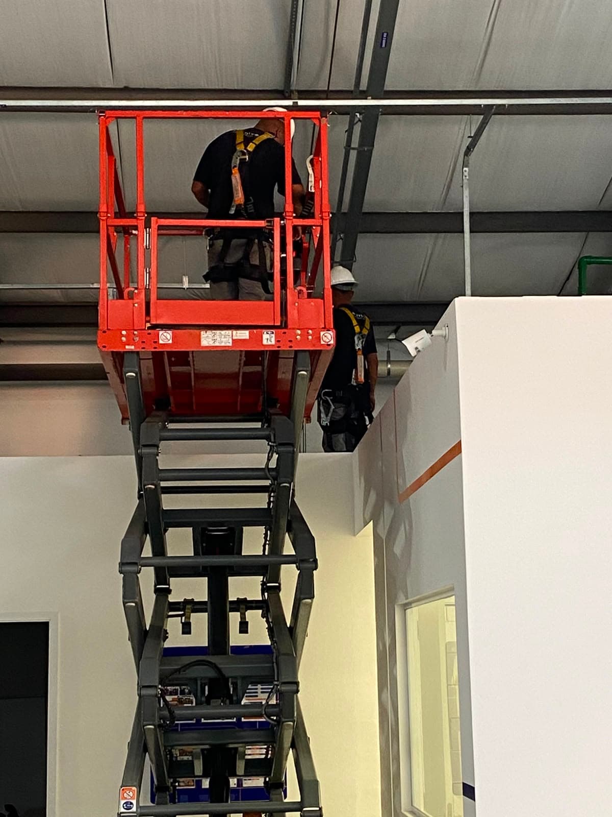 Dois técnicos da HD Tecnologia instalando infraestrutura de rede a partir de uma plataforma elevatória
