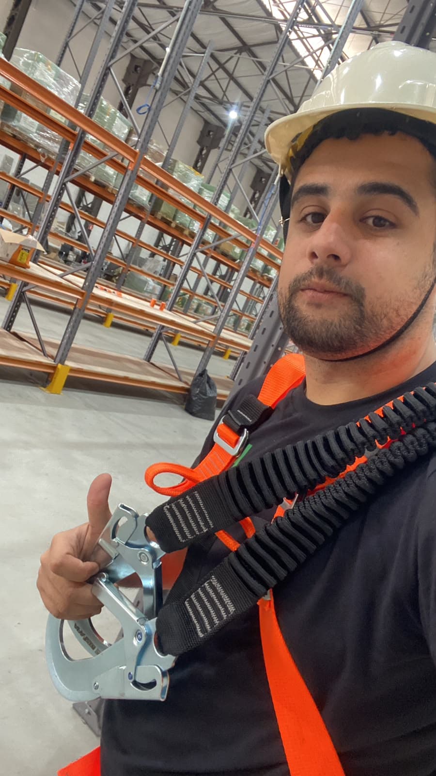 Técnico da HD Tecnologia com cinto e talabarte de segurança durante trabalho em altura em galpão